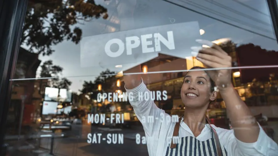 Girl hangs an Open Sign on a small business window